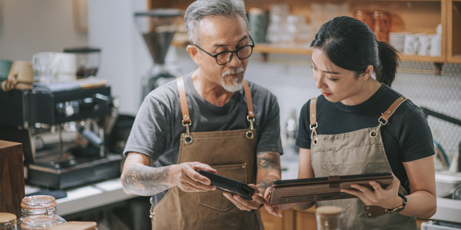 senior man owner and daughter using digital tablet at counter